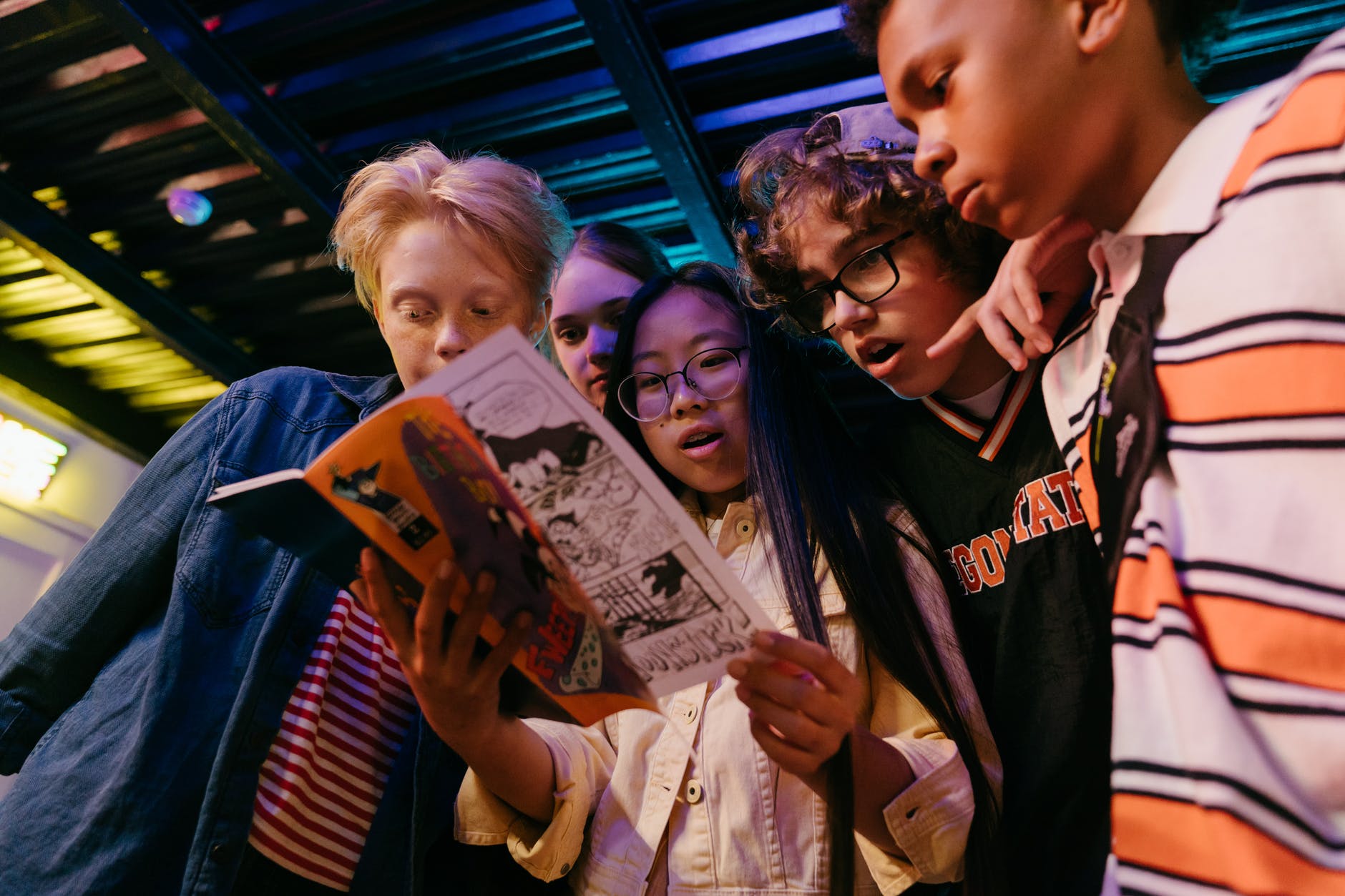 A group of teens appear surprised by a comic book.