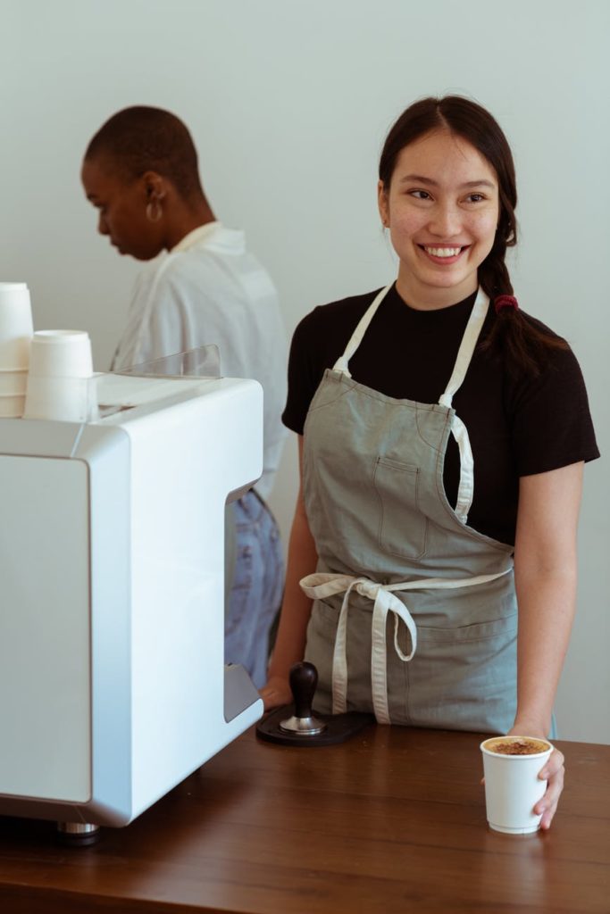 A woman at a coffee shop smiles as she serves coffee, but is she really happy with her work?