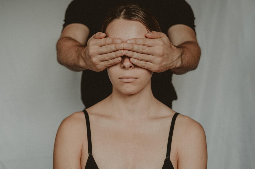 A man covers a woman's eyes.