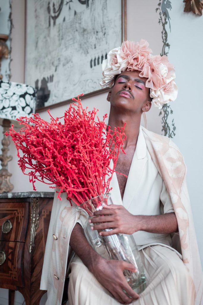 This man is wearing make-up, a floral headdress, and holding a bouquet, but is he queer? We don't know.