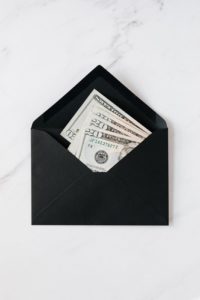 A black envelope with cash dollars on marble table.