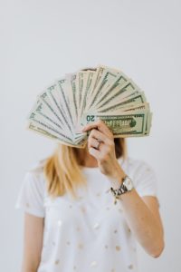A woman holding fan of US dollar bills, which is likely more money than some authors ever see.
